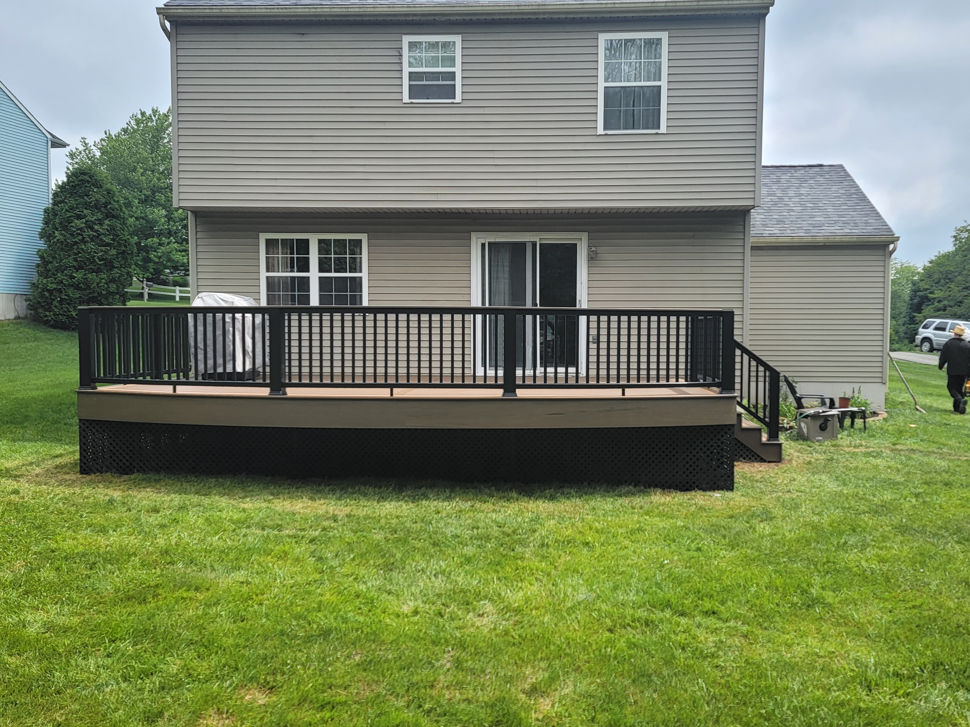Deck with black railing behind home